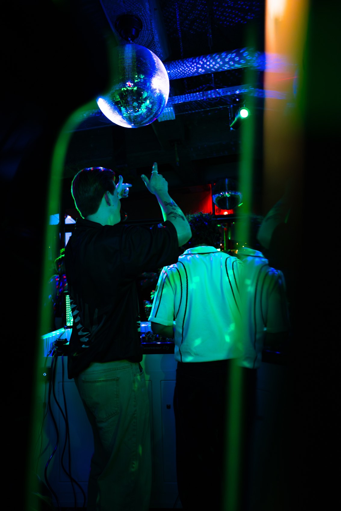 Two silhouettes under a mirror ball and a green laser