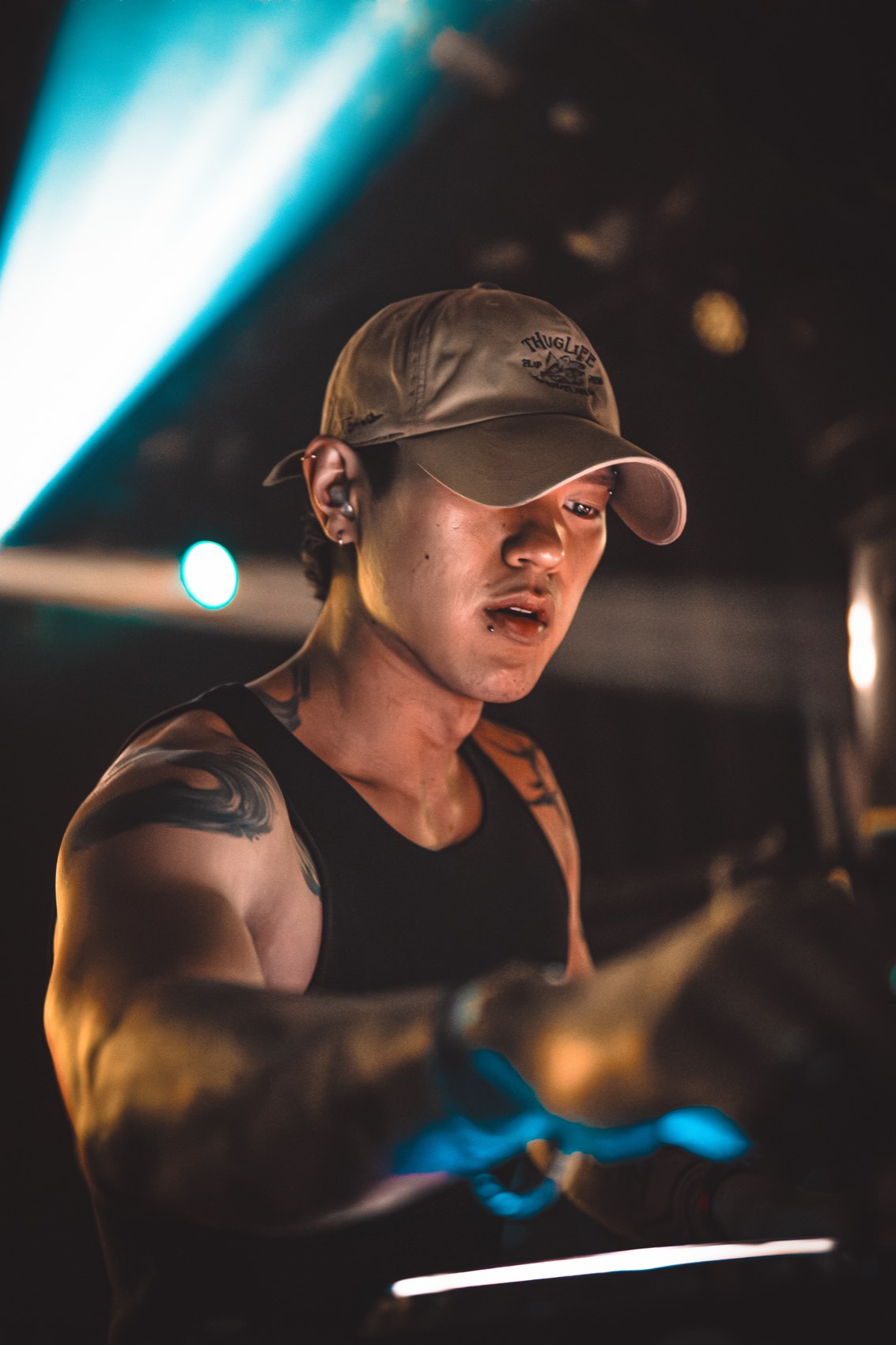 DJ in a cap lit by a teal beam and warm light