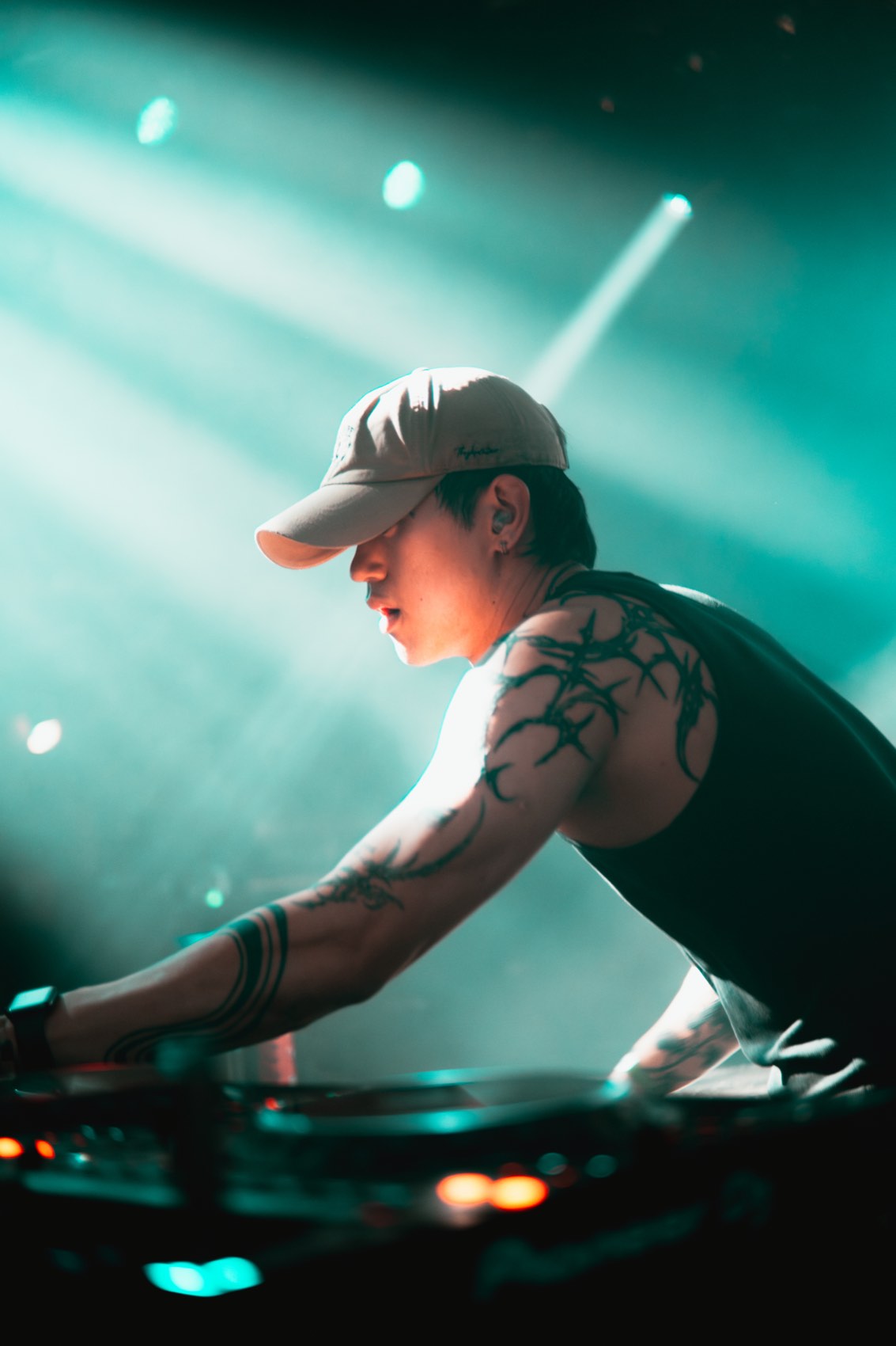 DJ over the decks in green teal beams